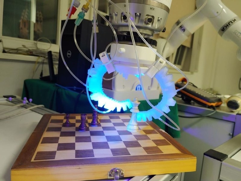Hydraulischer Soft-Greifer an einem Roboterarm über einem Schachbrett
